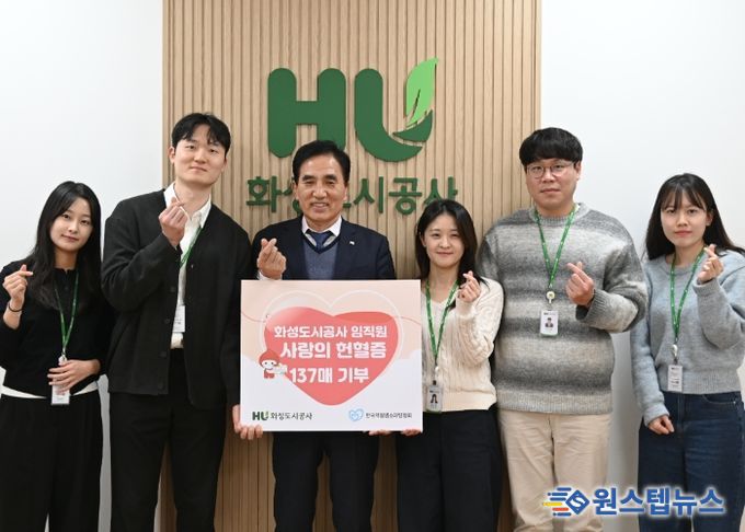 화성도시공사 한병홍 사장이 임직원들이 자발적으로 기부한 헌혈증 전달을 알리는 판넬을 들고 기념촬영을 하고 있다.