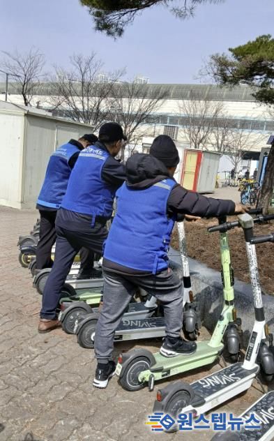 전동킥보드 안전 가이드 사업 참여자들이 무단방치된 전동킥보드를 정리하고 있다