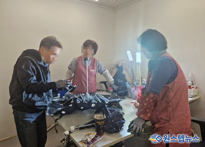 우산수리센터에서 고장난 우산을 수리하고 있고 있다.