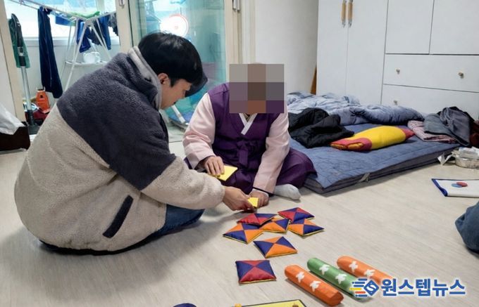치매 어르신과 후견인이 딱지치기 등 전통놀이를 체험하고 있다.