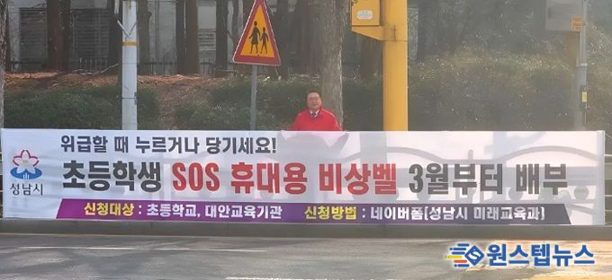황금석 성남시의원이 초등학교 인근에 설치된 ‘초등학생 SOS 휴대용 비상벨’ 신청 안내 현수막 앞에 서 있다