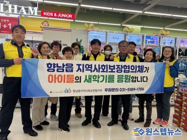 향남읍지역사회보장협의체 위원들이 ‘새 학기 봄맞이 바우처’ 지원사업 현수막을 들고 기념촬영을 하고 있다